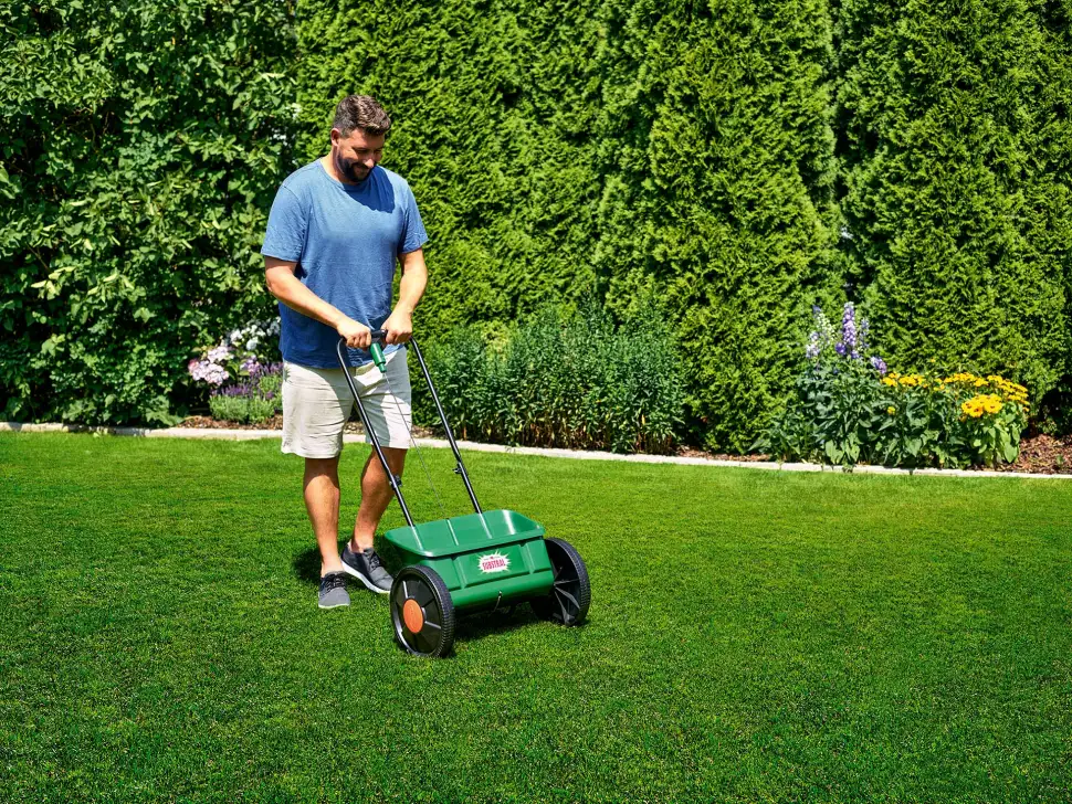 Mit einem Streuwagen wird der Rasendünger gleichmäßig auf der Fläche ausgebracht. Foto: Evergreen Garden Care/akz-o
