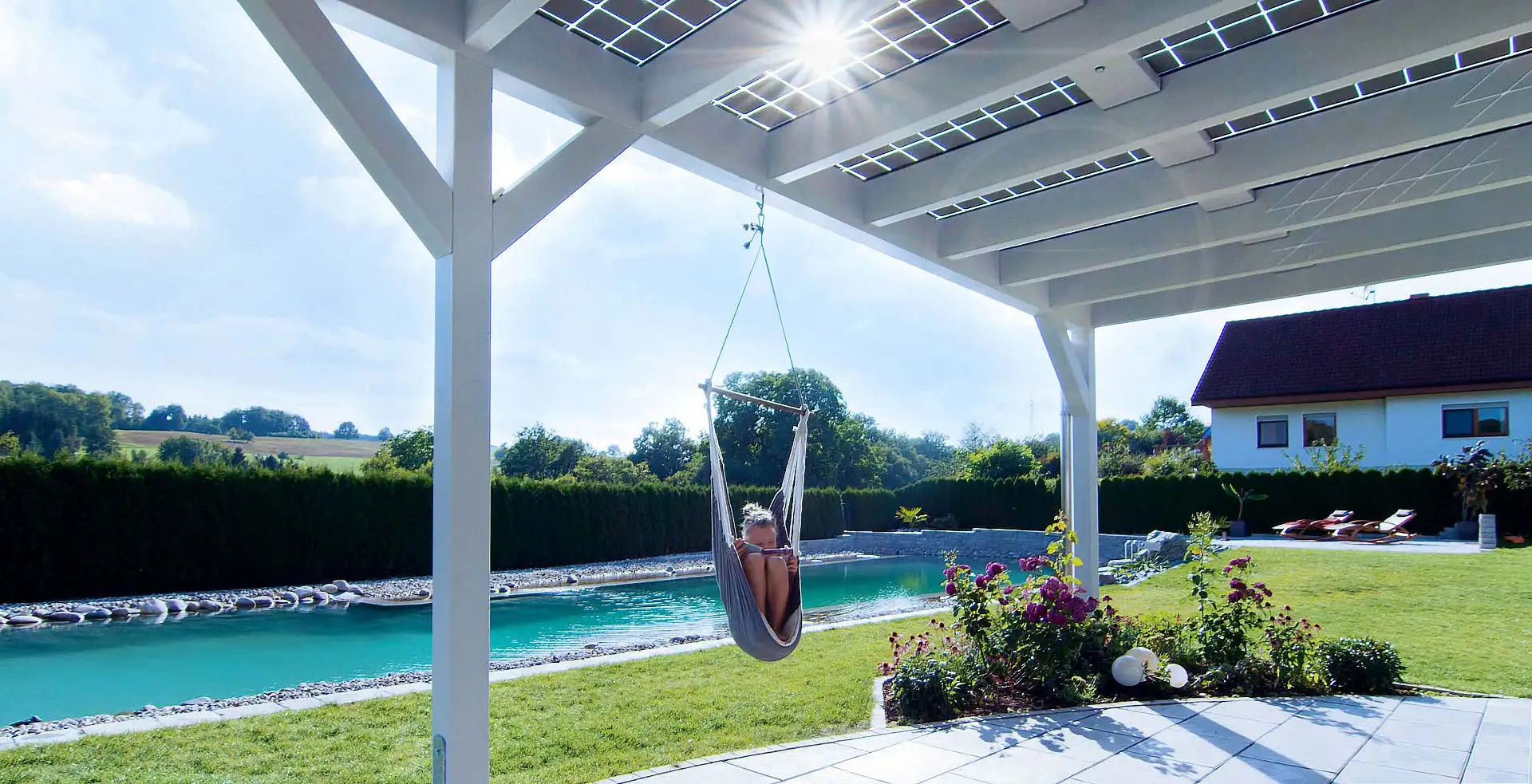 So lässt sich der Sommer genießen: gut geschützt unter dem Terrassendach mit Solarmodulen, die die Sonnenenergie in Strom für Kühlschrank & Co. umwandeln. (Foto: HLC/Solarterrassen & Carportwerk GmbH)